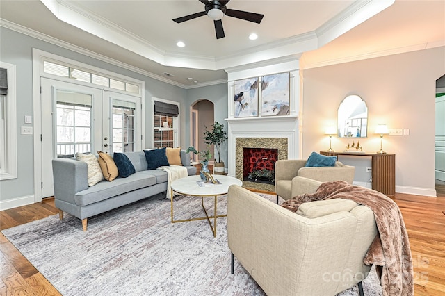 living room featuring french doors, wood-type flooring, ornamental molding, a tray ceiling, and ceiling fan