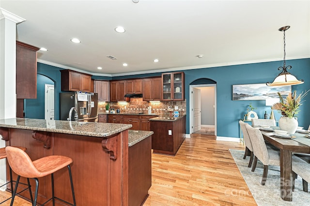 kitchen featuring a breakfast bar, tasteful backsplash, stainless steel fridge, kitchen peninsula, and light stone countertops