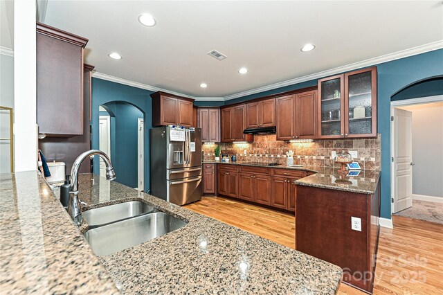 kitchen featuring sink, light stone countertops, and stainless steel refrigerator with ice dispenser