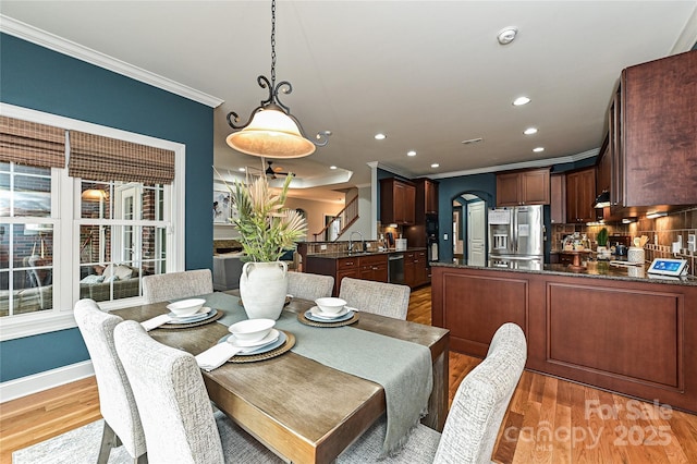 dining area featuring crown molding, sink, and light hardwood / wood-style flooring