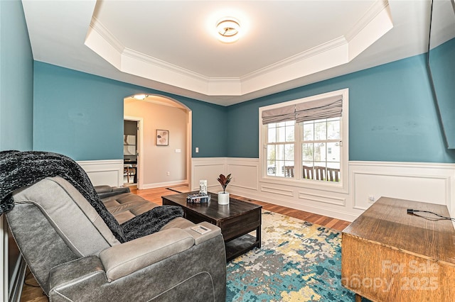 living room with hardwood / wood-style floors, ornamental molding, and a raised ceiling