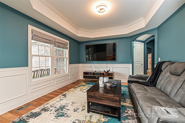 living room with ornamental molding, a tray ceiling, and hardwood / wood-style floors