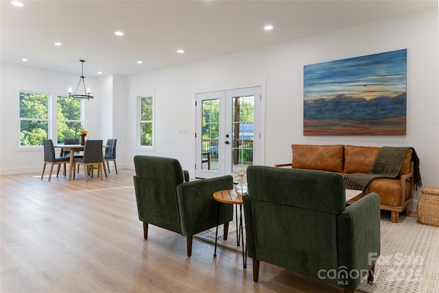 living room with an inviting chandelier, light wood-type flooring, and french doors