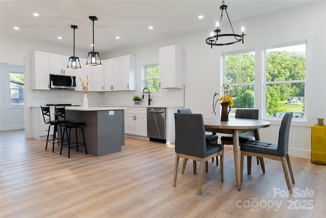 kitchen featuring white cabinetry, tasteful backsplash, decorative light fixtures, appliances with stainless steel finishes, and a kitchen island