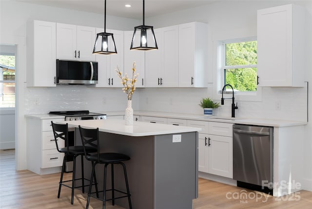 kitchen with appliances with stainless steel finishes, sink, a kitchen island, and white cabinets