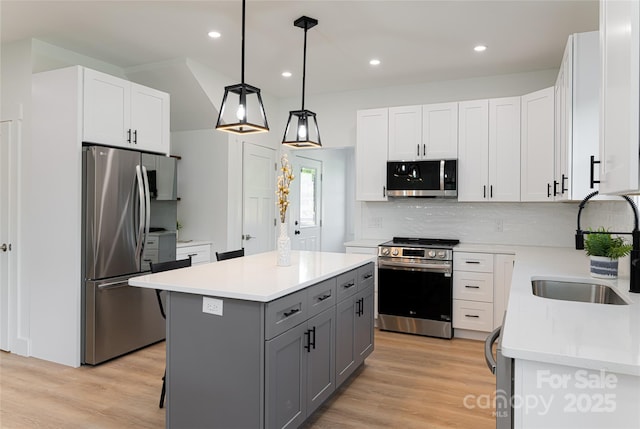 kitchen with a kitchen island, sink, gray cabinetry, white cabinets, and stainless steel appliances