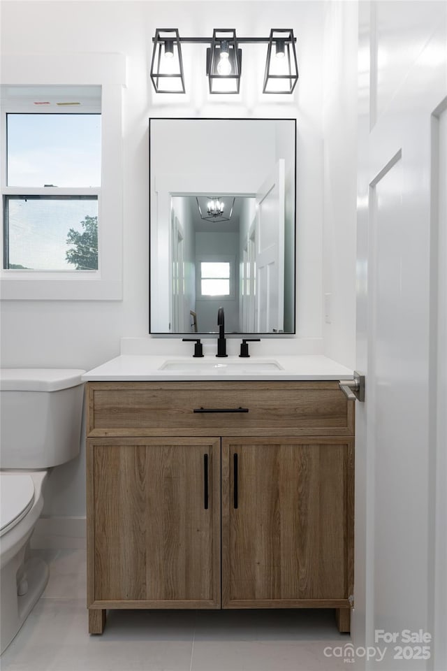 bathroom with tile patterned floors, toilet, a chandelier, and vanity