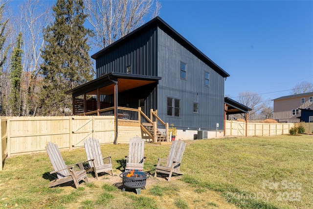 rear view of property with a yard, cooling unit, and an outdoor fire pit