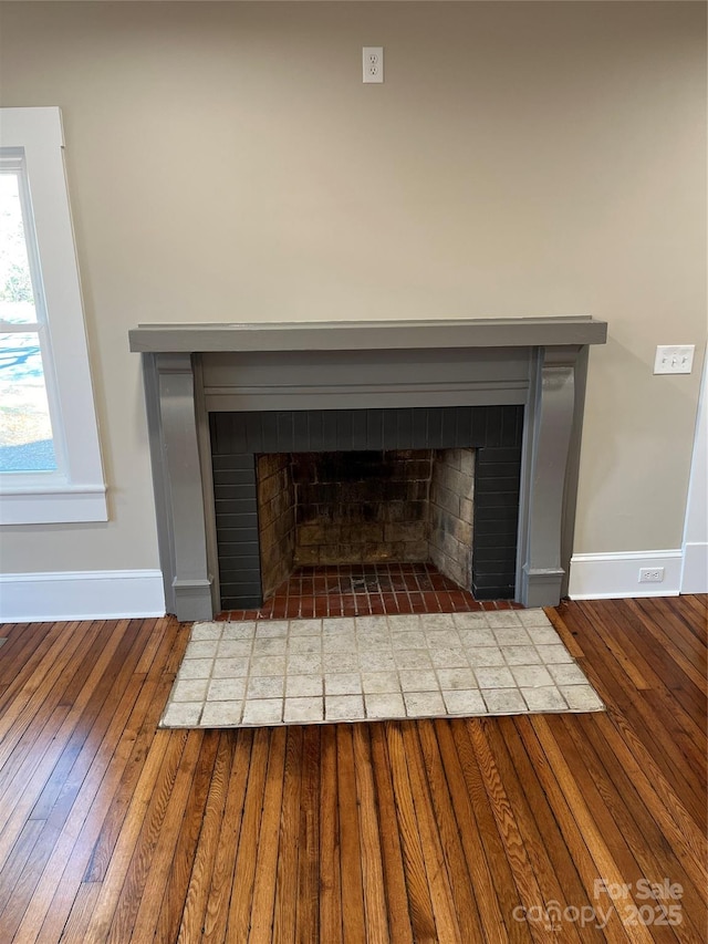 room details featuring a brick fireplace and wood-type flooring