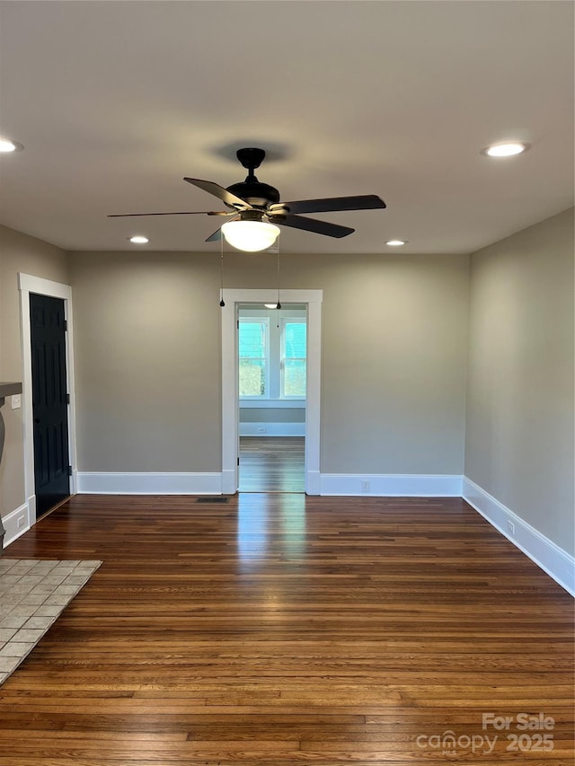 empty room with ceiling fan and dark hardwood / wood-style flooring