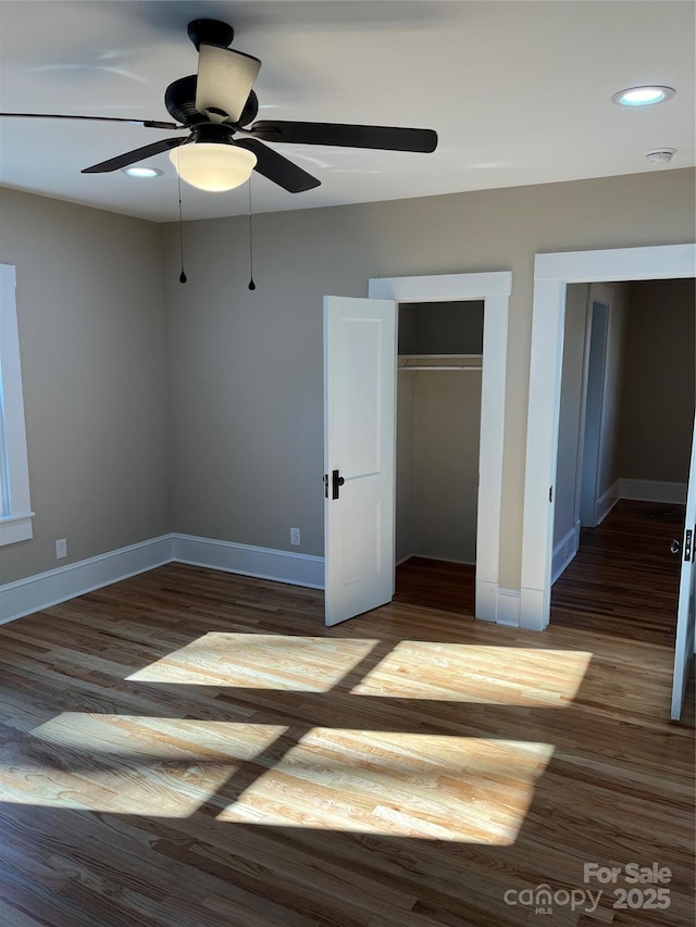 unfurnished bedroom with dark hardwood / wood-style flooring, a closet, and ceiling fan