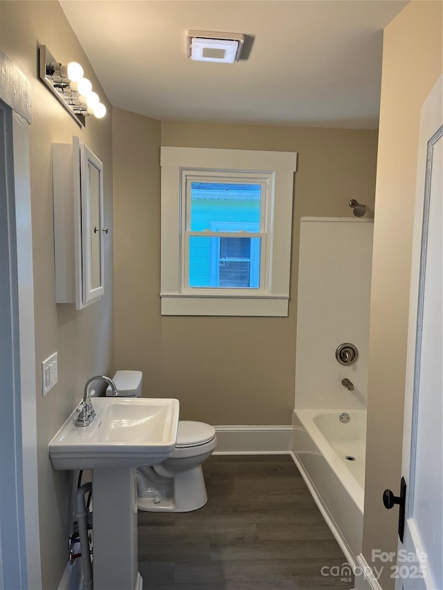 bathroom with toilet, hardwood / wood-style flooring, and shower / washtub combination