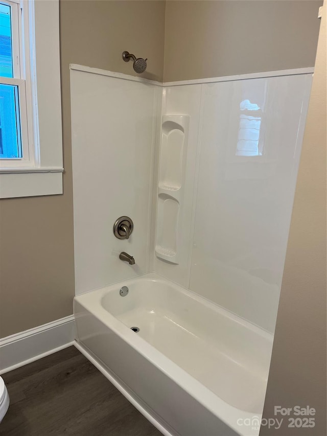 bathroom with toilet, washtub / shower combination, and hardwood / wood-style flooring