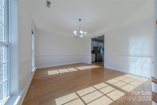 empty room featuring ornamental molding, a chandelier, and hardwood / wood-style flooring