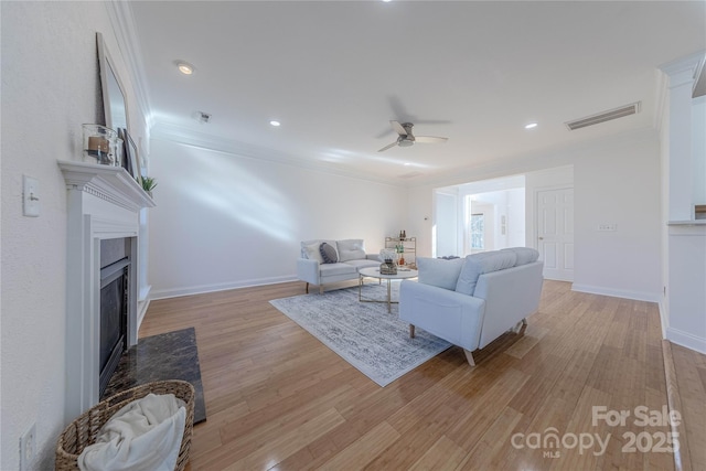 living room featuring ceiling fan, crown molding, and light hardwood / wood-style flooring