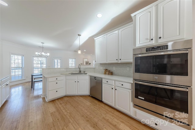 kitchen featuring white cabinetry, kitchen peninsula, appliances with stainless steel finishes, pendant lighting, and sink