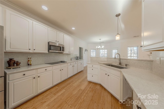 kitchen with pendant lighting, sink, crown molding, white cabinetry, and stainless steel appliances