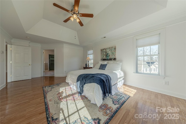 bedroom featuring ceiling fan, ornamental molding, hardwood / wood-style flooring, and a tray ceiling