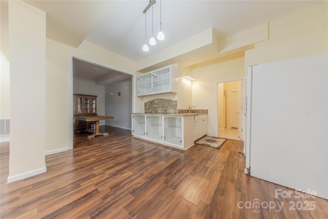 kitchen with white cabinetry, white refrigerator, sink, hanging light fixtures, and dark hardwood / wood-style floors