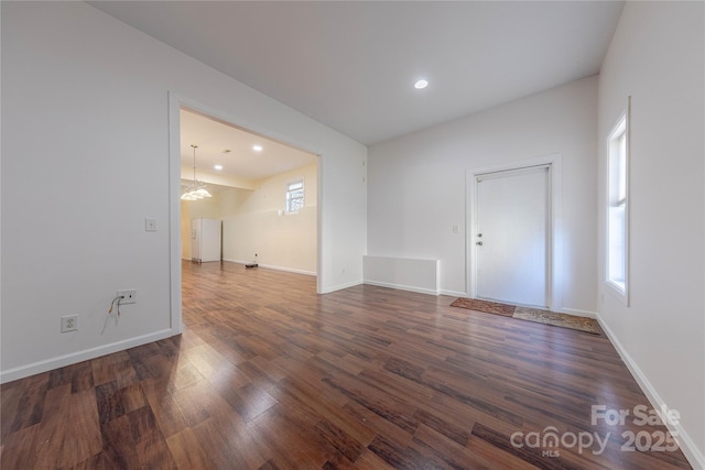 unfurnished room with dark wood-type flooring and a notable chandelier