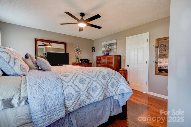 bedroom featuring ceiling fan, wood-type flooring, and a textured ceiling