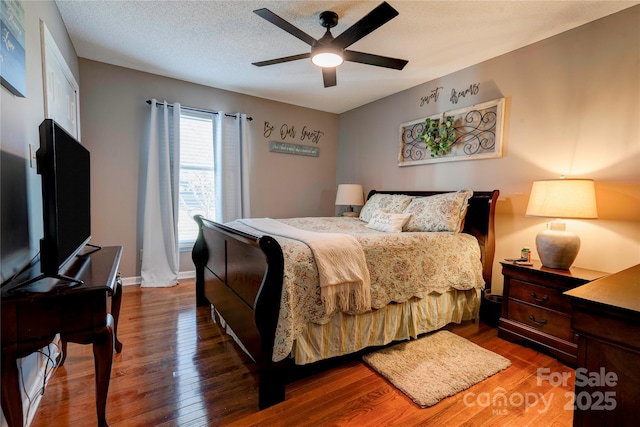 bedroom with ceiling fan, dark hardwood / wood-style floors, and a textured ceiling