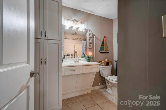 bathroom featuring vanity, toilet, tile patterned flooring, and a textured ceiling