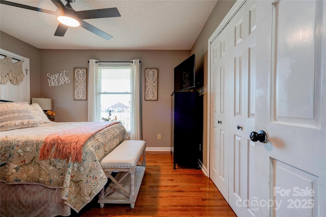 bedroom featuring hardwood / wood-style flooring, a textured ceiling, a closet, and ceiling fan