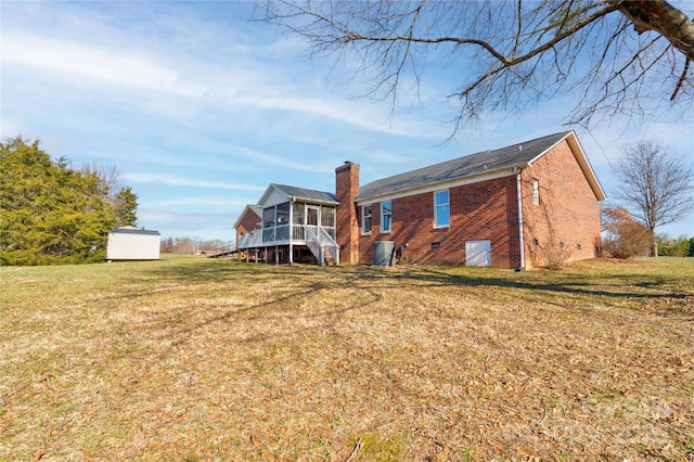 rear view of house featuring a sunroom and a lawn