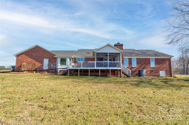 rear view of property featuring a wooden deck, a yard, a sunroom, and central air condition unit