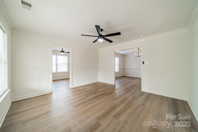 empty room featuring crown molding, a wealth of natural light, ceiling fan with notable chandelier, and light wood-type flooring