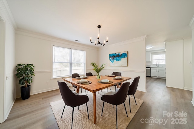 dining room featuring crown molding, sink, light wood-type flooring, and a notable chandelier