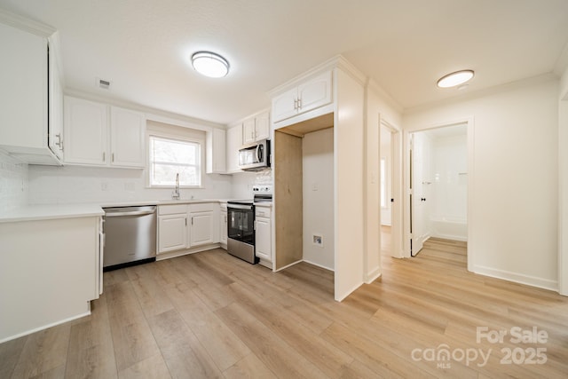 kitchen with stainless steel appliances, white cabinets, backsplash, and light hardwood / wood-style floors