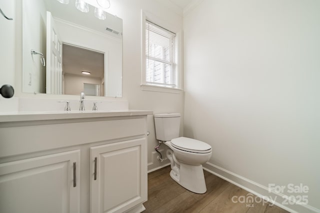 bathroom featuring hardwood / wood-style flooring, vanity, ornamental molding, and toilet