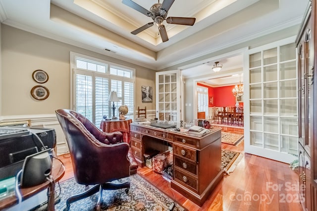 office featuring ceiling fan, ornamental molding, a tray ceiling, and light hardwood / wood-style flooring