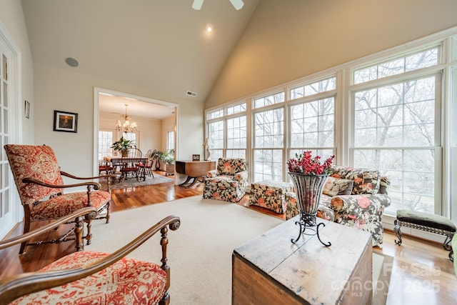 sunroom featuring ceiling fan with notable chandelier and vaulted ceiling