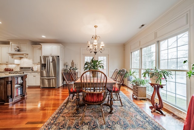 dining area featuring a notable chandelier, crown molding, and light hardwood / wood-style floors