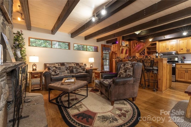 living room featuring light wood-style floors, beam ceiling, and track lighting