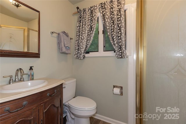 full bathroom with baseboards, vanity, toilet, and an enclosed shower