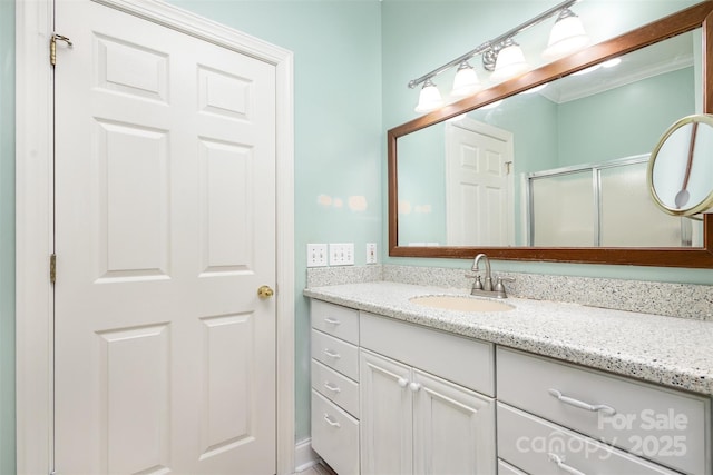 bathroom with vanity, a shower with shower door, and crown molding