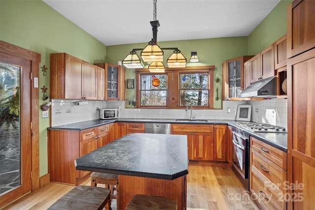 kitchen with light hardwood / wood-style flooring, pendant lighting, a center island, a kitchen bar, and sink