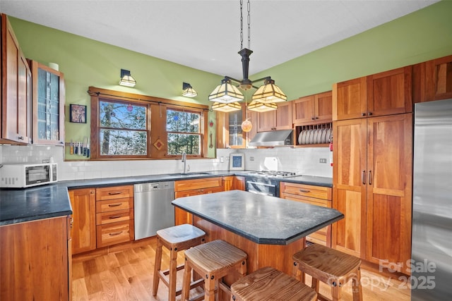 kitchen with light hardwood / wood-style flooring, decorative light fixtures, stainless steel appliances, a breakfast bar, and a kitchen island