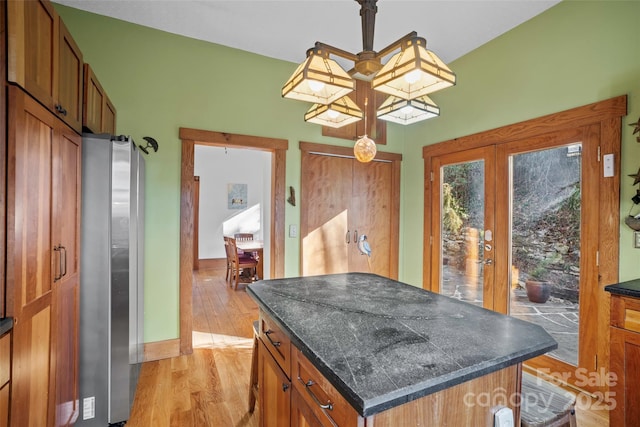 kitchen featuring pendant lighting, a center island, french doors, stainless steel fridge, and light wood-type flooring