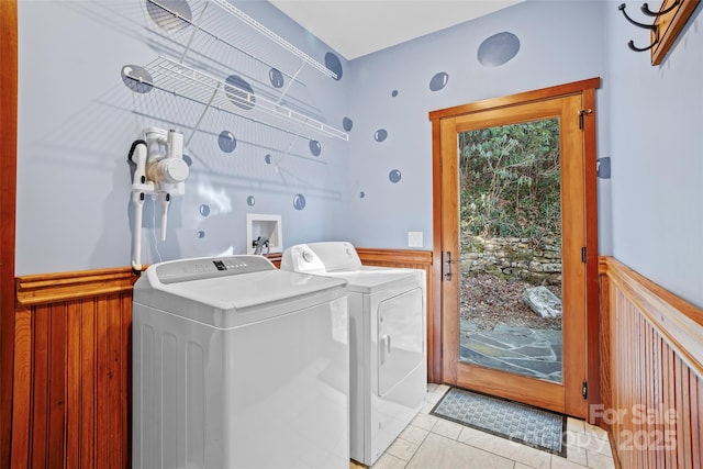 washroom with washer and clothes dryer, wooden walls, and light tile patterned floors