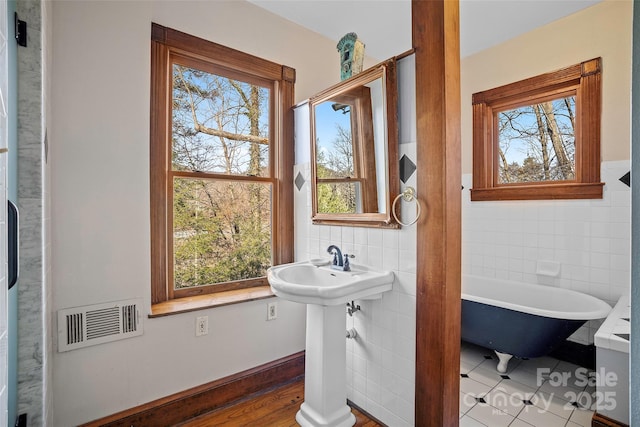 bathroom featuring tile walls, sink, a bathtub, and tile patterned floors