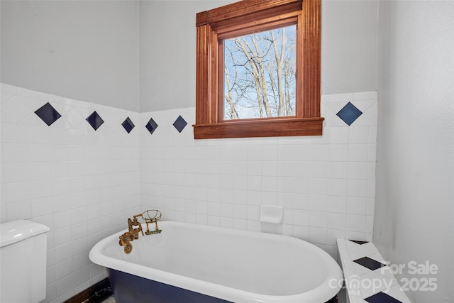 bathroom featuring tile walls, a tub, and toilet