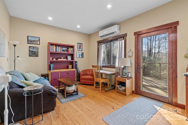 sitting room with a wall unit AC and hardwood / wood-style flooring