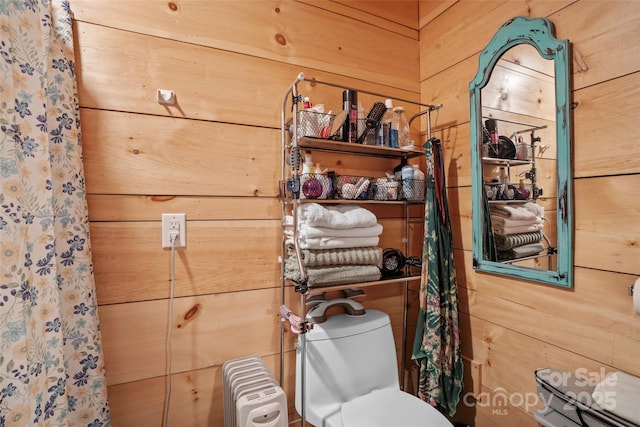 bathroom with toilet, wood walls, and radiator