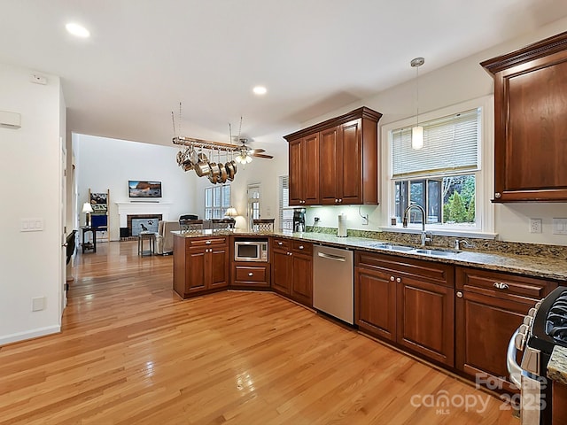 kitchen with sink, hanging light fixtures, appliances with stainless steel finishes, kitchen peninsula, and light hardwood / wood-style floors