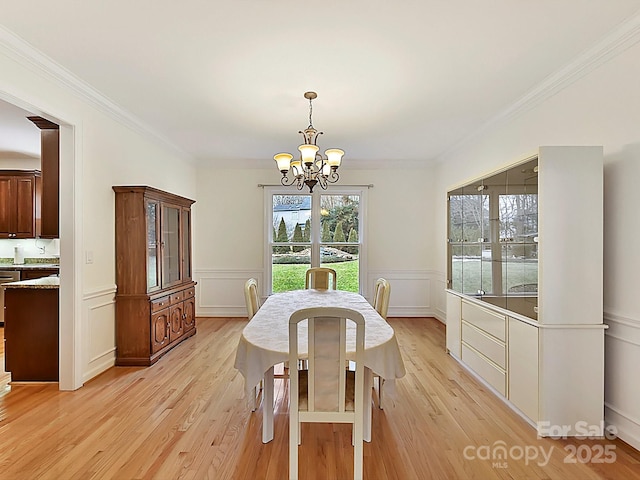 dining area featuring ornamental molding, light hardwood / wood-style floors, and a chandelier